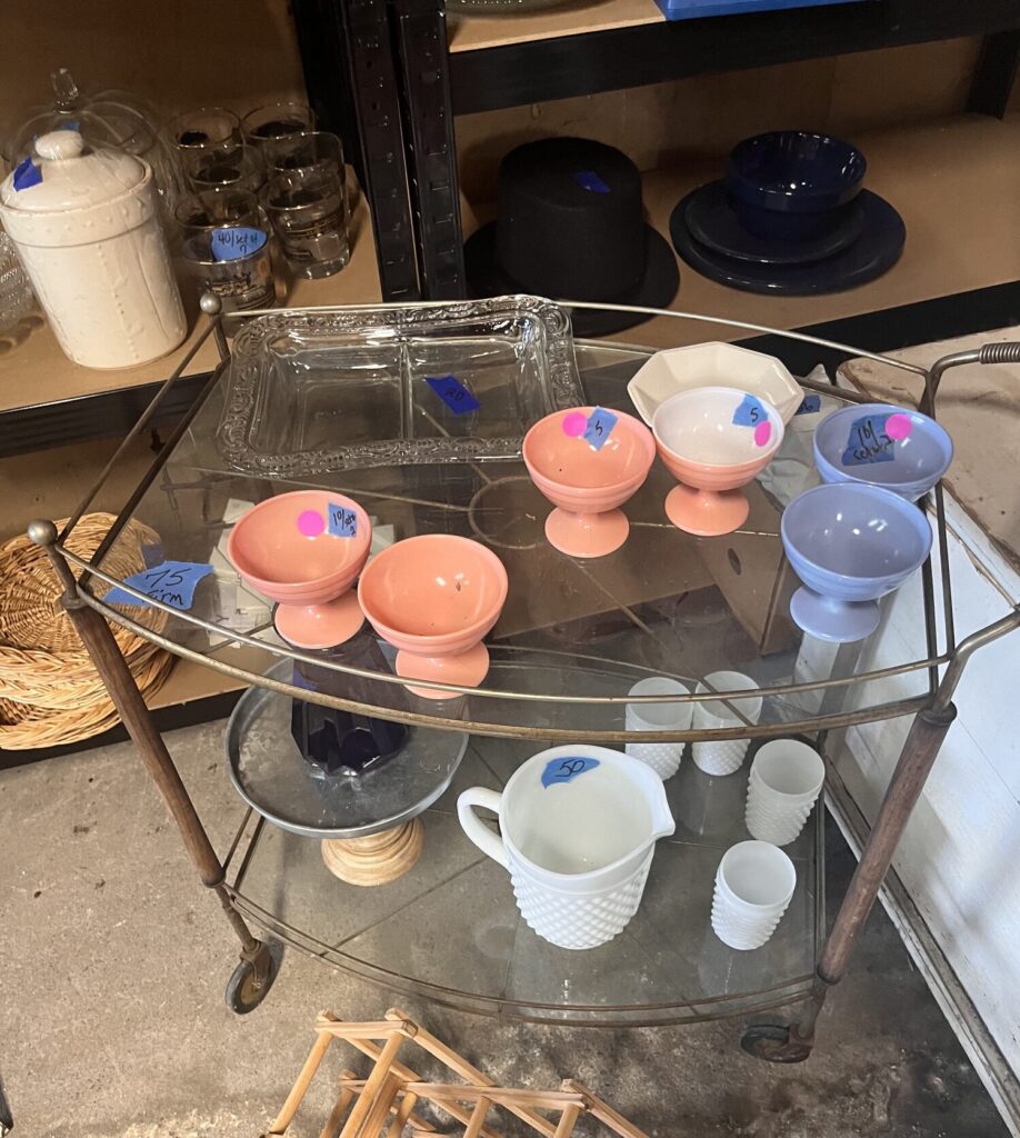Vintage dishes and glassware organized on rolling carts during estate sale preparation